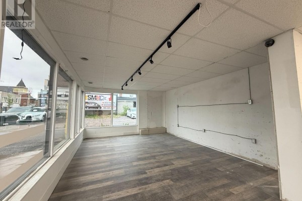 Empty commercial space with dark wood-look laminate flooring, track lighting, and large street-facing windows. - 4 - 390 Muskoka Road S, Gravenhurst)