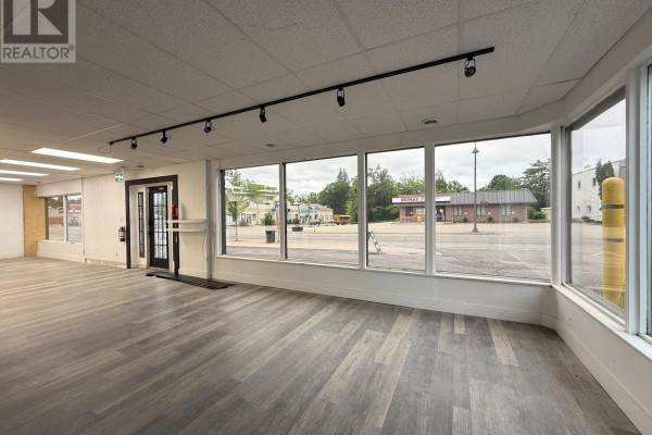 View of the street from inside the empty commercial space, featuring large windows and laminate flooring. - 4 - 390 Muskoka Road S, Gravenhurst)