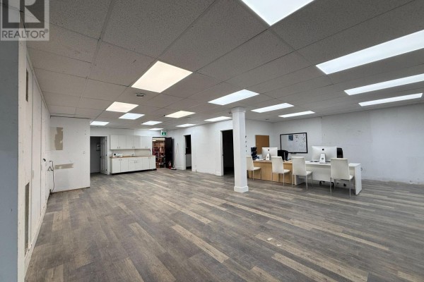Large, open commercial space with laminate flooring, white ceiling tiles, and a small reception area. - 4 - 390 Muskoka Road S, Gravenhurst)