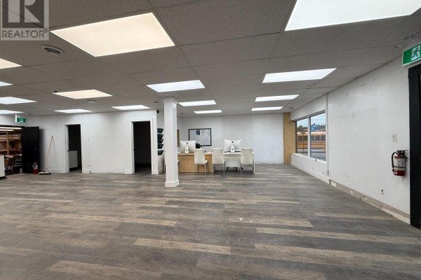 Interior view of a spacious commercial area with laminate flooring, fluorescent lighting, and a reception desk. - 4 - 390 Muskoka Road S, Gravenhurst)