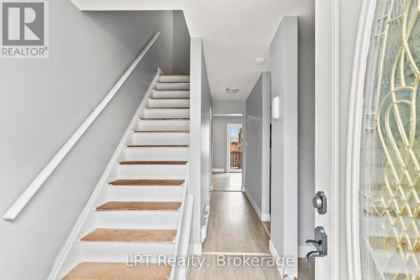 Interior foyer with light wood floor, grey walls, and white staircase. - 4 - 4 Tiffany Place, Quinte West