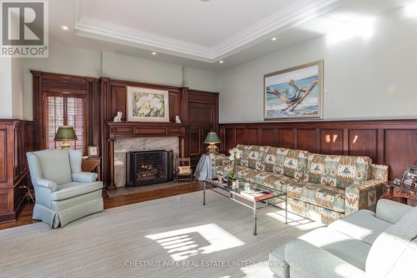 Living room with a sofa, chairs, fireplace, and wooden paneled walls. - 4 - 40 Maple Avenue, Toronto