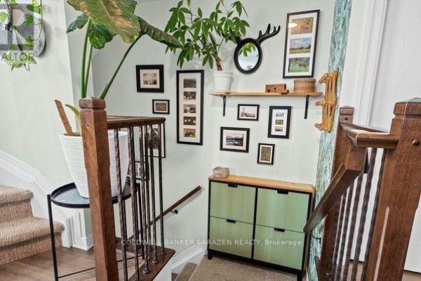 Interior view of a staircase landing with a green cabinet, artwork, and plants. - 4 - 4443 Harper Avenue, Ottawa