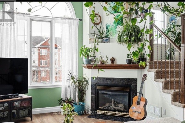 Living room with a fireplace, a large window, numerous houseplants, and a guitar. - 4 - 4443 Harper Avenue, Ottawa