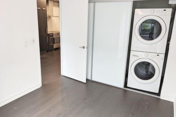 Laundry closet with stacked white washer and dryer, viewed from the bedroom. - 4 - 455 Front Street E, Toronto