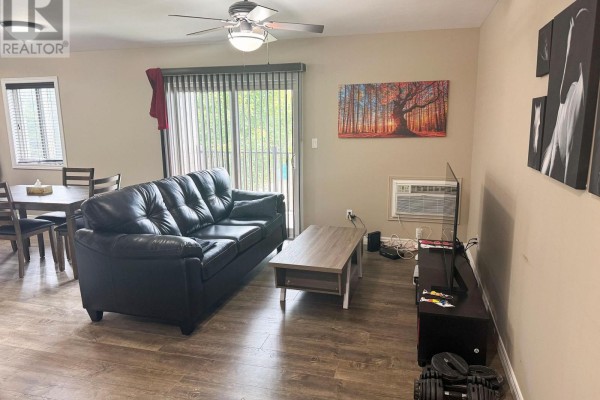 Living room with a black sofa, coffee table, television, and a dining area. - 4 - 50 South Street E, Aylmer
