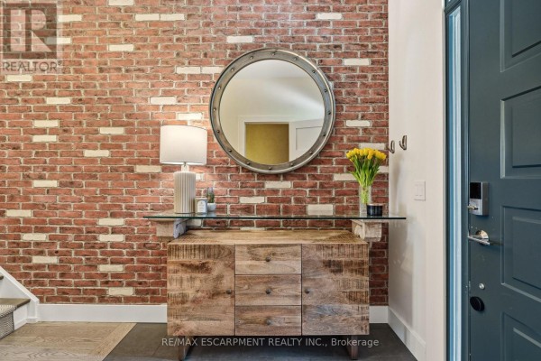 Close-up of a console table with a vase of yellow tulips against a red brick wall. - 4 - 5056 New Street, Burlington