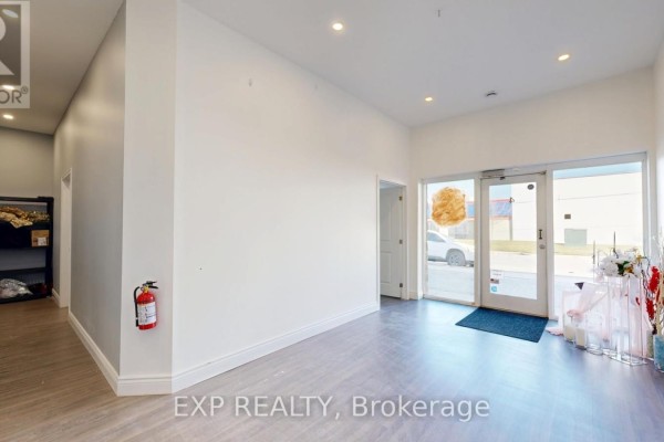 Interior of a commercial space with white walls, wood-look flooring, and large glass entrance doors. - 4 - 540 Clarke Road, London East