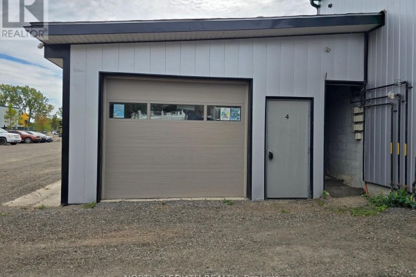 Close-up of a beige garage door and gray entry door on a commercial building. - 4 - 543 Greenwich Street, Brantford