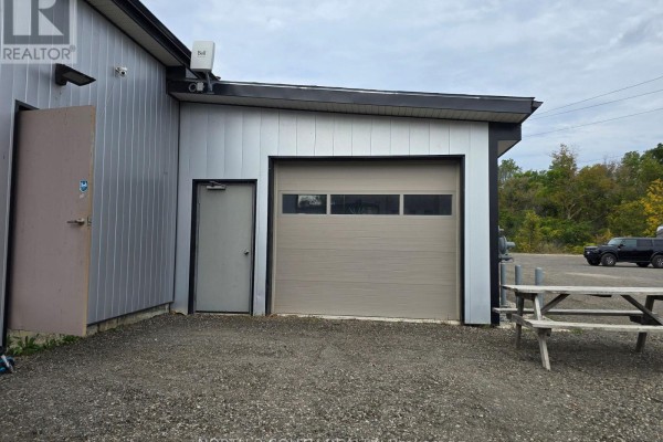 Exterior commercial building with gray metal siding, a beige garage door, and an entry door. - 4 - 543 Greenwich Street, Brantford