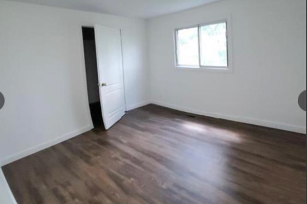 An empty bedroom with white walls, a closet, and dark wood laminate flooring. - 4 - 564 Lyons Lane, Oakville