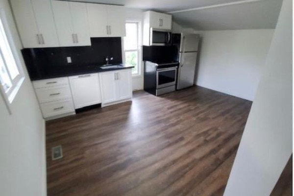 A small kitchen with white cabinets, black granite countertops, stainless steel appliances, and wood laminate flooring. - 4 - 564 Lyons Lane, Oakville