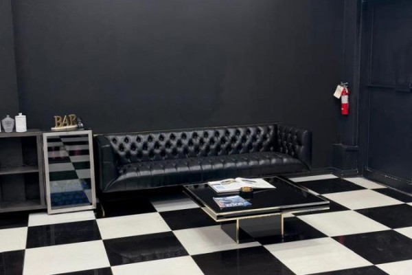 Waiting area with a black tufted sofa, a black coffee table, and black and white checkered flooring. - #4 - 5657 Hwy 7, Vaughan