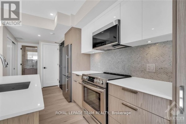 Close-up view of the kitchen's tiled backsplash, stainless steel stove, and quartz countertops. - 4 - 58 Florence Street, Ottawa