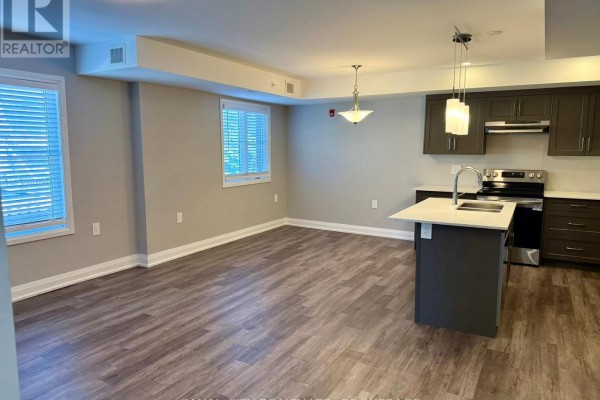 Modern kitchen with dark cabinets, white countertops, stainless steel refrigerator, and island. - 4 - 6 Ann Street, Thorold