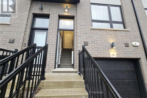 Exterior of a townhouse complex with grey brick and large windows under a blue sky. - 4 - 720 Grey Street, Brantford