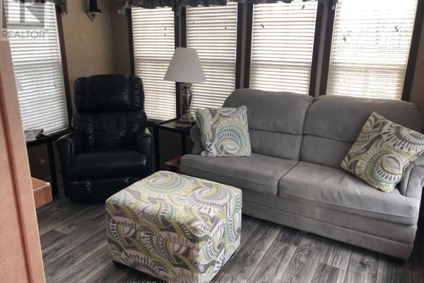 Cozy sunroom featuring a gray sofa, black recliner, and patterned ottoman - 4 - 77719 Bluewater Highway, Central Huron