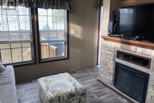Living room with stone fireplace, TV, and large windows providing natural light - 4 - 77719 Bluewater Highway, Central Huron