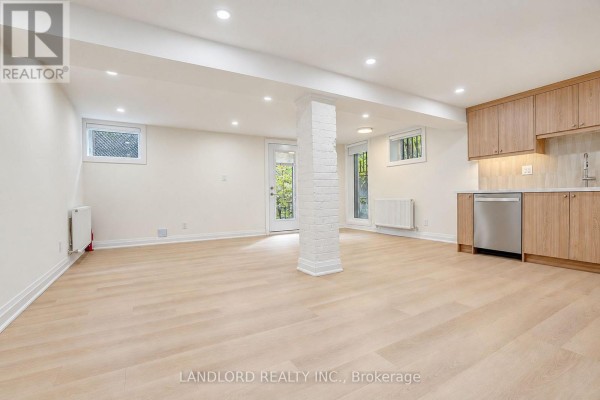 Spacious open concept room with light wood floors and a central brick pillar. - 4 - 92 Neville Park Boulevard, Toronto