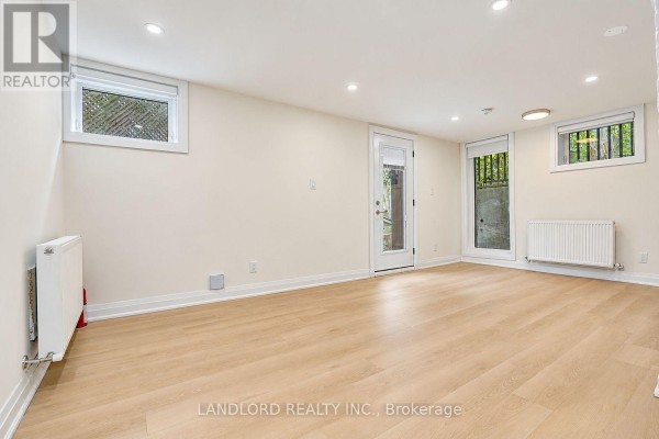 Bright room with light wood floors, white walls, and multiple windows and doors. - 4 - 92 Neville Park Boulevard, Toronto