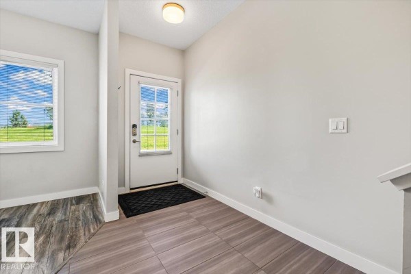 Interior entryway with beige carpeted stairs and wood-look tile flooring. - #4 1636 Kerr Rd Nw, Edmonton