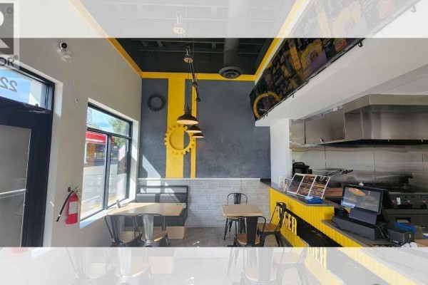 Dining area with booth seating and tables against a gray and yellow gear-themed wall. - 4 2230 Cliffe Ave, Courtenay