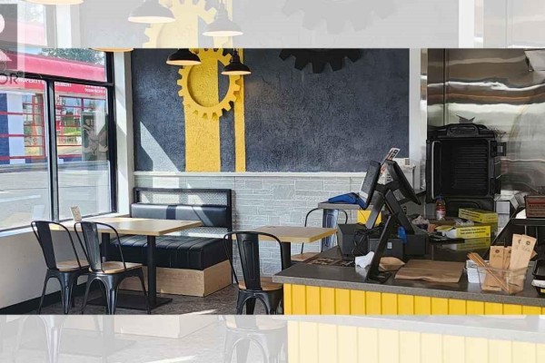 Seating area with long counter tables and chairs, plus smaller tables by large windows. - 4 2230 Cliffe Ave, Courtenay
