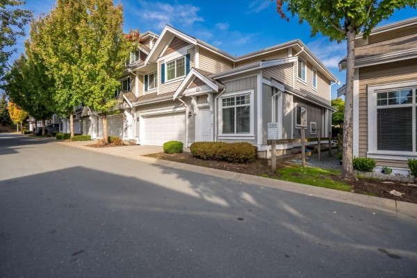 Side view of a townhouse complex with trees and a paved driveway. - 4 30748 Cardinal Avenue, Abbotsford