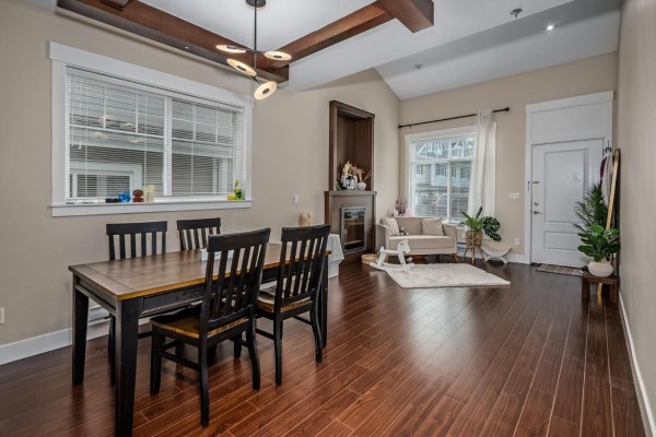 Living and dining area with a dark wood table, fireplace, and hardwood floors. - 4 30748 Cardinal Avenue, Abbotsford