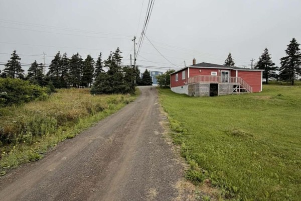 Gravel road leads uphill past a red house with a wooden deck and green lawn. - 4-6 Lahey's Lane, Wabana
