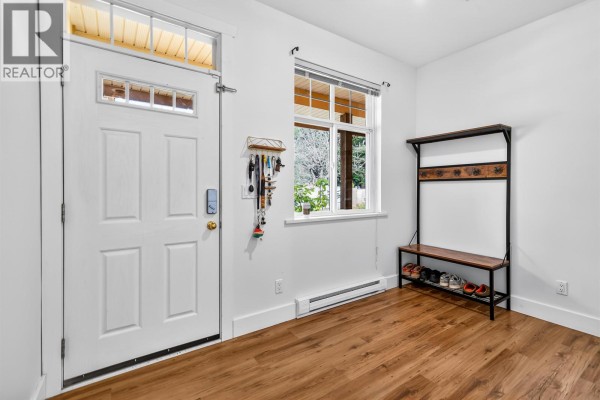 Entryway with a white door, wooden floor, and a bench with shoe rack. - 4 809 North Road, Gibsons