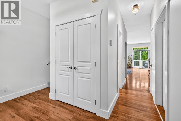 Hallway with white double doors, wooden floor, and entrance to living area. - 4 809 North Road, Gibsons