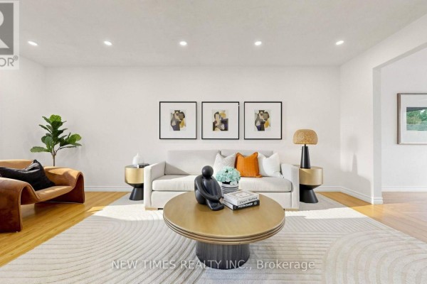 Living room featuring a neutral-toned sofa, stylish chairs, and a round coffee table with decorative items. - 4 Ashstead Place, Toronto