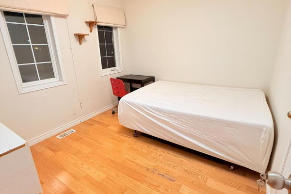 Bedroom with light wood floors, a single bed, a red chair, and a desk against the wall. - 4 Attilio Street, Markham