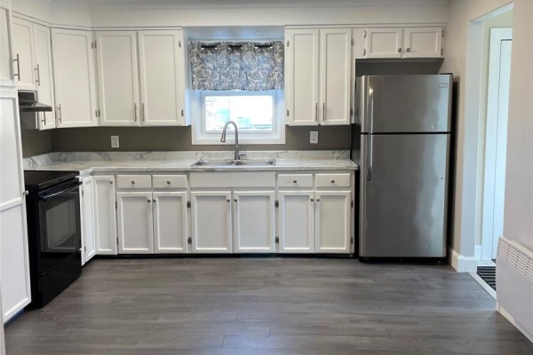 A spacious kitchen featuring white cabinetry, stainless steel refrigerator, and dark grey flooring. - 4 Bay Street, Little Burnt Bay