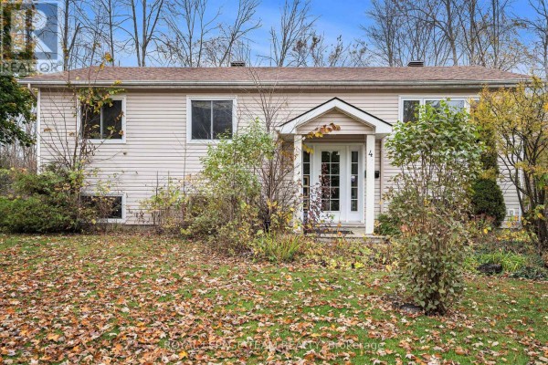 Close-up of the front entrance of a beige vinyl-sided bungalow with fall foliage. - 4 Black Walnut Road, North Grenville