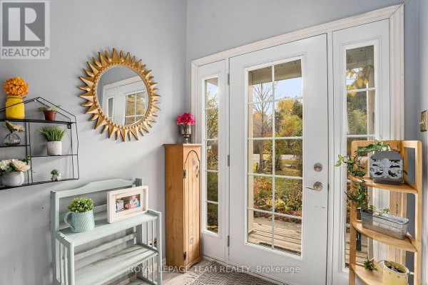 Interior view of a home entranceway with double glass doors, decorative shelves, and a sunburst mirror. - 4 Black Walnut Road, North Grenville