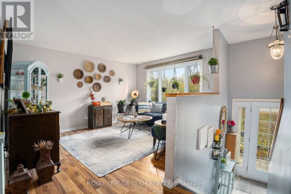 Living room with hardwood floors, a large rug, sofa, coffee table, and a view of the outdoors. - 4 Black Walnut Road, North Grenville