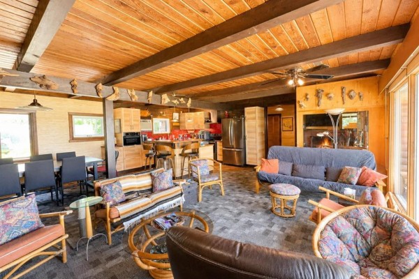 Open-concept living and dining area with a fireplace, kitchen island, and wood-paneled ceiling. - 4 Block 4 Road, Otterfalls