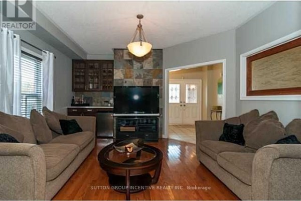 Living room with brown sofas, a large television, a wet bar, and a stone accent wall. - 4 Bluewater Trail, Barrie