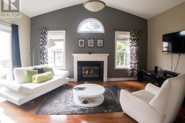 Living room with a white sofa, a fireplace with a white mantel, and large windows. - 4 Bluewater Trail, Barrie