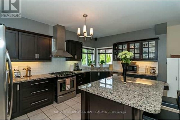 Modern kitchen with dark wood cabinets, granite countertops, and stainless steel appliances. - 4 Bluewater Trail, Barrie