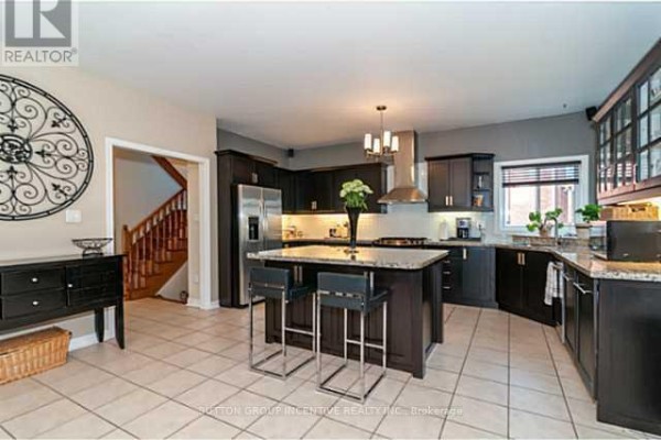 Spacious kitchen with a large island, dark cabinets, granite countertops, and tile flooring. - 4 Bluewater Trail, Barrie