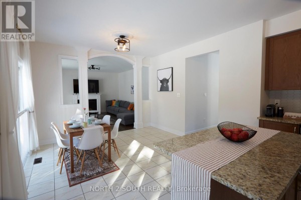 Dining area with table and chairs, open to living room with fireplace, and kitchen island - 4 Boville Court Oro Medonte