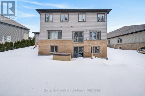 Backyard of the house with a walkout basement, hot tub, and snow-covered lawn. - 4 Boville Court, Oro Medonte