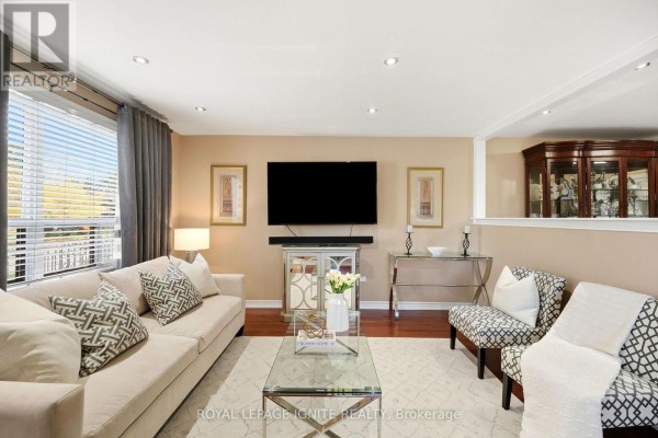 Living room with a sofa, chairs, coffee table, fireplace, and television. - 4 Buttercup Court, Toronto