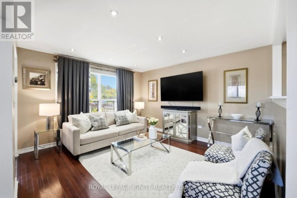 Living room with a sofa, chairs, coffee table, fireplace, and television and hardwood floors. - 4 Buttercup Court, Toronto