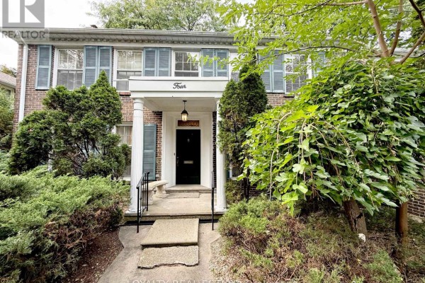 Front entrance of a two-story brick house with a covered porch, pillars, and blue shutters. - 4 Canadiana Drive, Markham