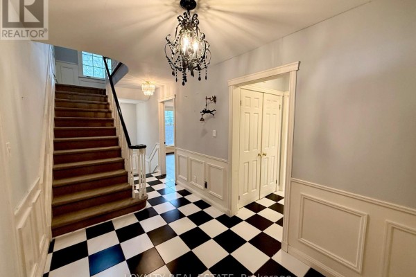 Interior foyer with a black and white checkered tile floor, grand staircase, and chandelier. - 4 Canadiana Drive, Markham