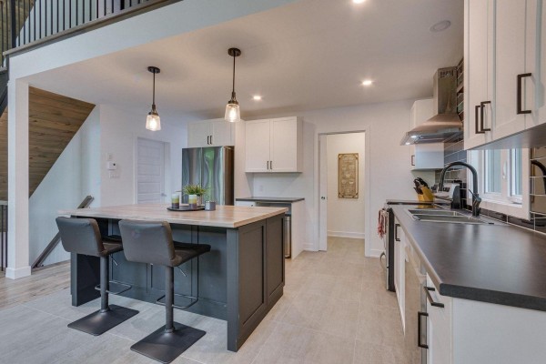 Kitchen with a dark island, white cabinets, stainless steel appliances, and pendant lights. - 4 Ch. Des Contes, Notre Dame De Pontmain